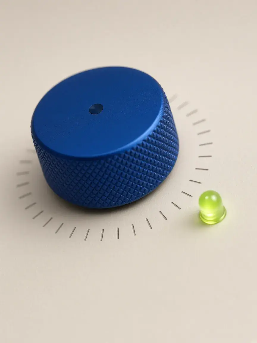 A knurled cobalt knob beside a lime indicator light on a bone-coloured panel