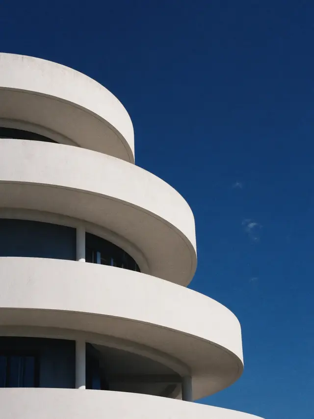 Curved white balconies stacked against a deep blue sky
