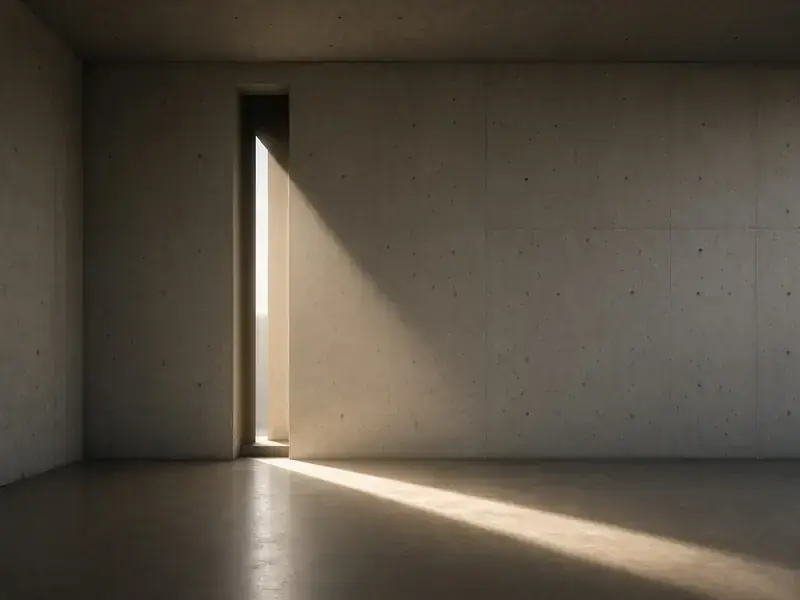 An empty concrete room with a narrow window casting a beam of light across the floor